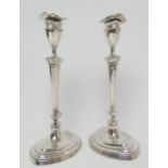 Pair of Edwardian silver candlesticks, London 1909, having an urn shaped sconce over tapered oval