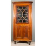 A late Georgian Oak Two Tier Corner Cupboard, the upper part with moulded cornice fitted three