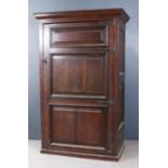 An Old Panelled Oak Hall Cupboard with moulded cornice enclosed by a single triple fielded