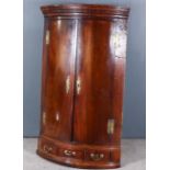 An 18th Century Mahogany Bow Front Hanging Corner Cupboard, with moulded and dentil cornice, the