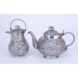 An Indian Silvery Metal Circular Bulbous Tea Pot and Similar Baluster Ewer and Cover, each chased