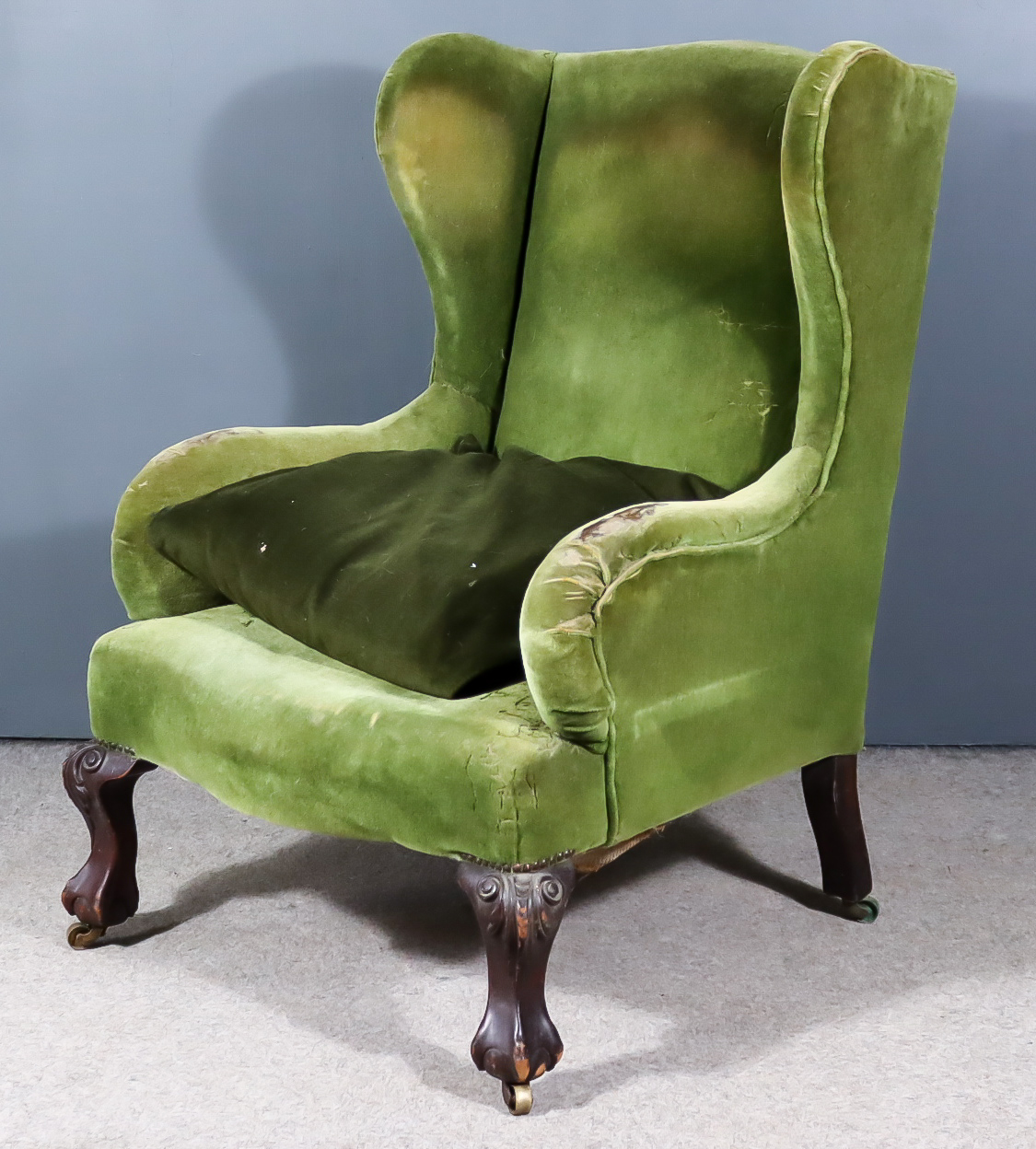 An Early 20th Century Wing Back Easy Chair, upholstered in green dralon, on carved cabriole front