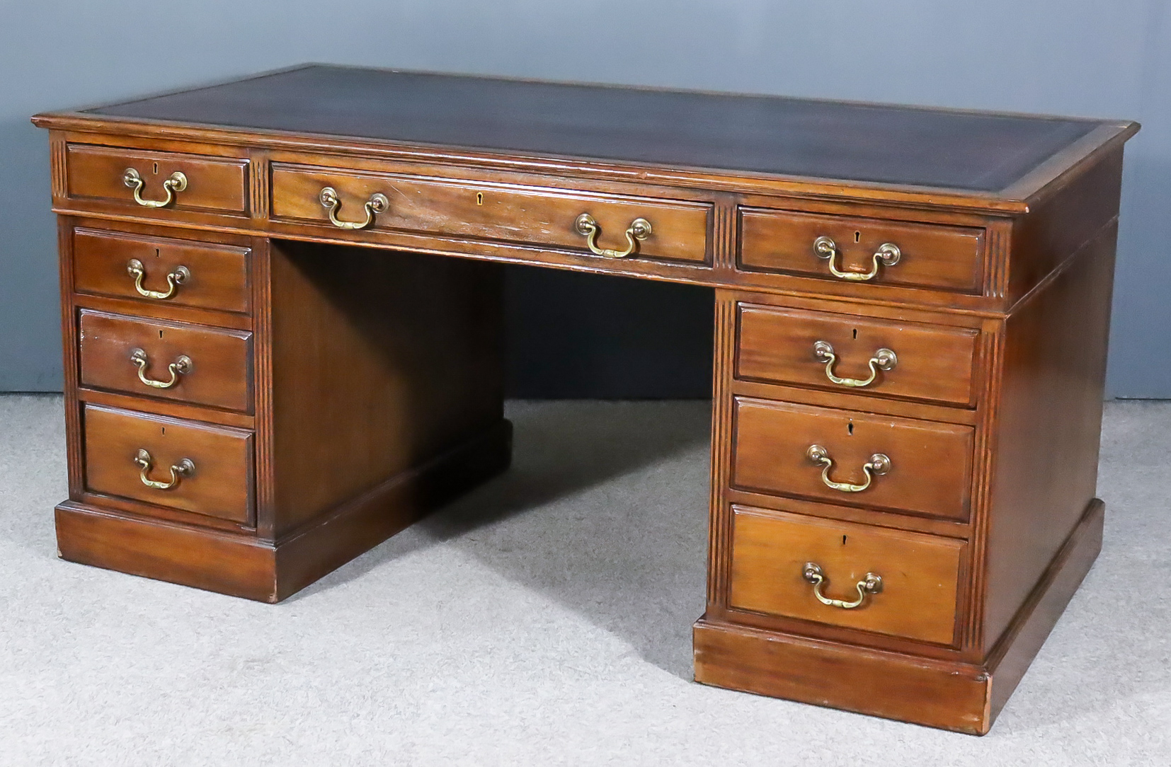 A Late Victorian Mahogany Kneehole Desk, with red tooled leather inset to top, fitted nine