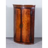 An 18th Century Oak Bow Front Hanging Corner Cupboard, inlaid with mahogany bandings enclosed by a