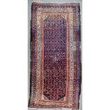 An Early 20th Century Seneh Long Rug, woven in colours, with stylised urn and floral ornament, on