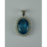 A Blue Topaz and Diamond Pendant, Modern, white metal mount set with a centre oval topaz stone,