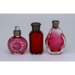 An Edward VII Silver Topped Cranberry Glass Scent Bottle and Two Other Scent Bottles, the