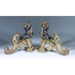 A Pair of French Brass and Bronzed Chenet, cast with putti and scrolls, 8.5ins high