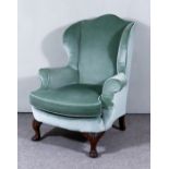 An Early 20th Century Wingback Easy Chair, upholstered in green dralon, on carved cabriole front