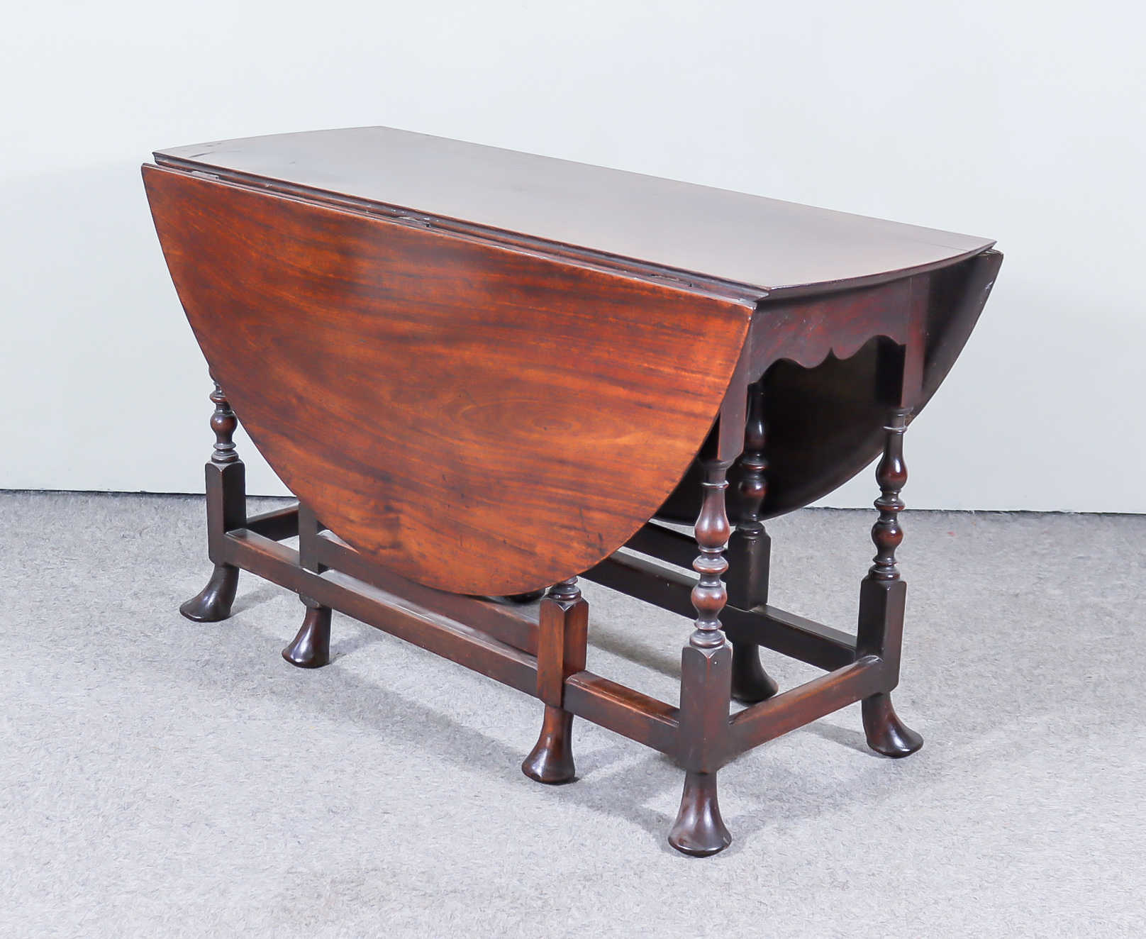 An Early 18th Century Mahogany Oval Gateleg Table, on turned supports with pad feet, 55ins x 47ins x