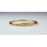 A Diamond Stiff Bangle, 20th Century, yellow metal set with seventeen small brilliant cut