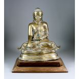 A Cast Brass Figure of a Seated Buddha, 14.5ins (36.9cm) high with wooden stand