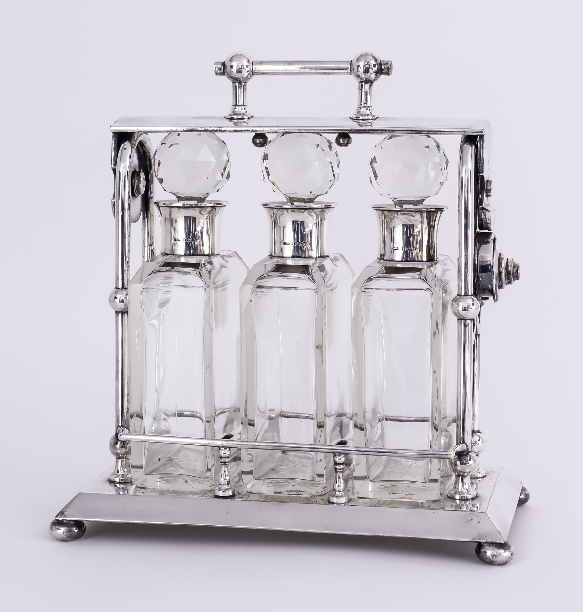 An Early 20th Century Plated Three Division Rectangular Tantalus of "Art Deco" design, on flat bun