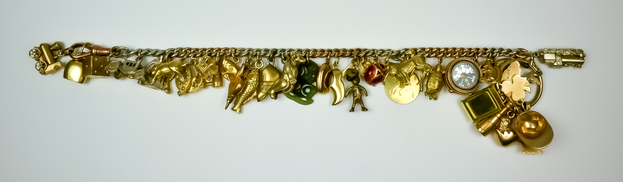 A 9ct Gold Three Coloured Charm Bracelet, suspended with thirty-two 9ct and gold coloured metal