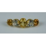 A Yellow and White Topaz Brooch, Modern, yellow metal set with two white and three yellow faceted