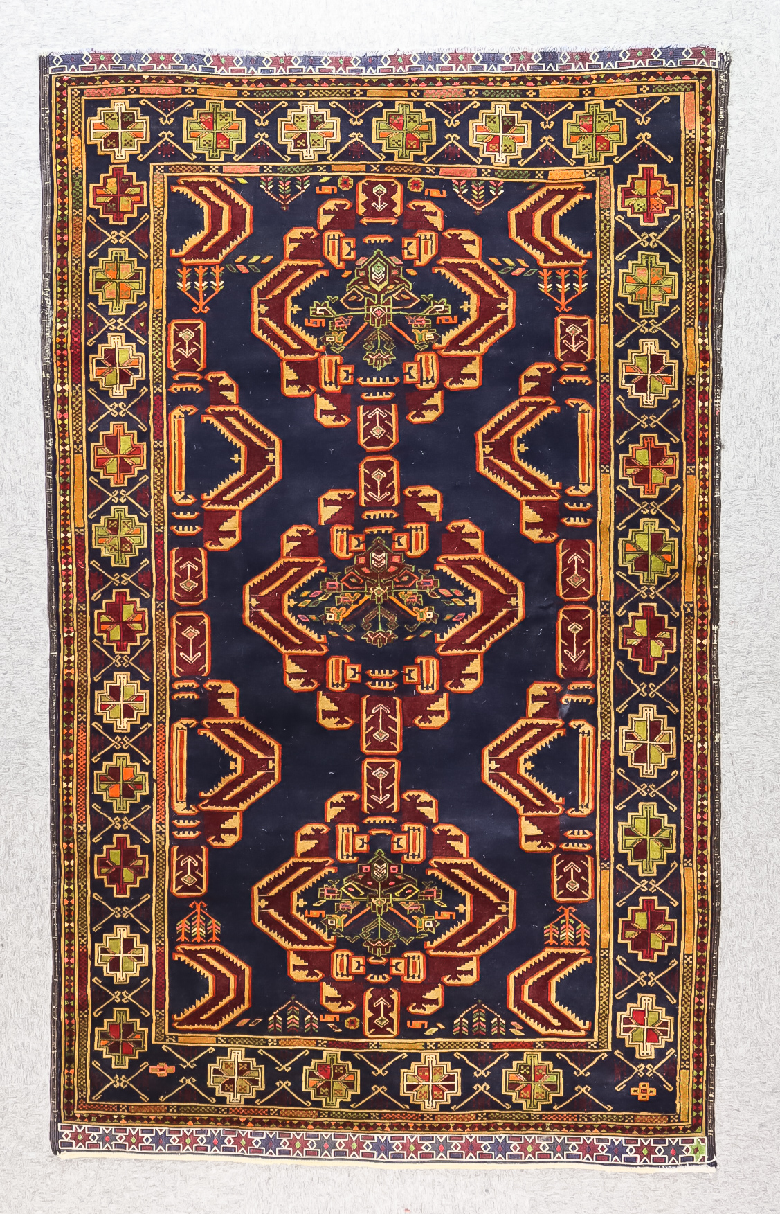 A Late 20th Century Rug of Persian Design, woven in colours of navy blue, wine and green, with three