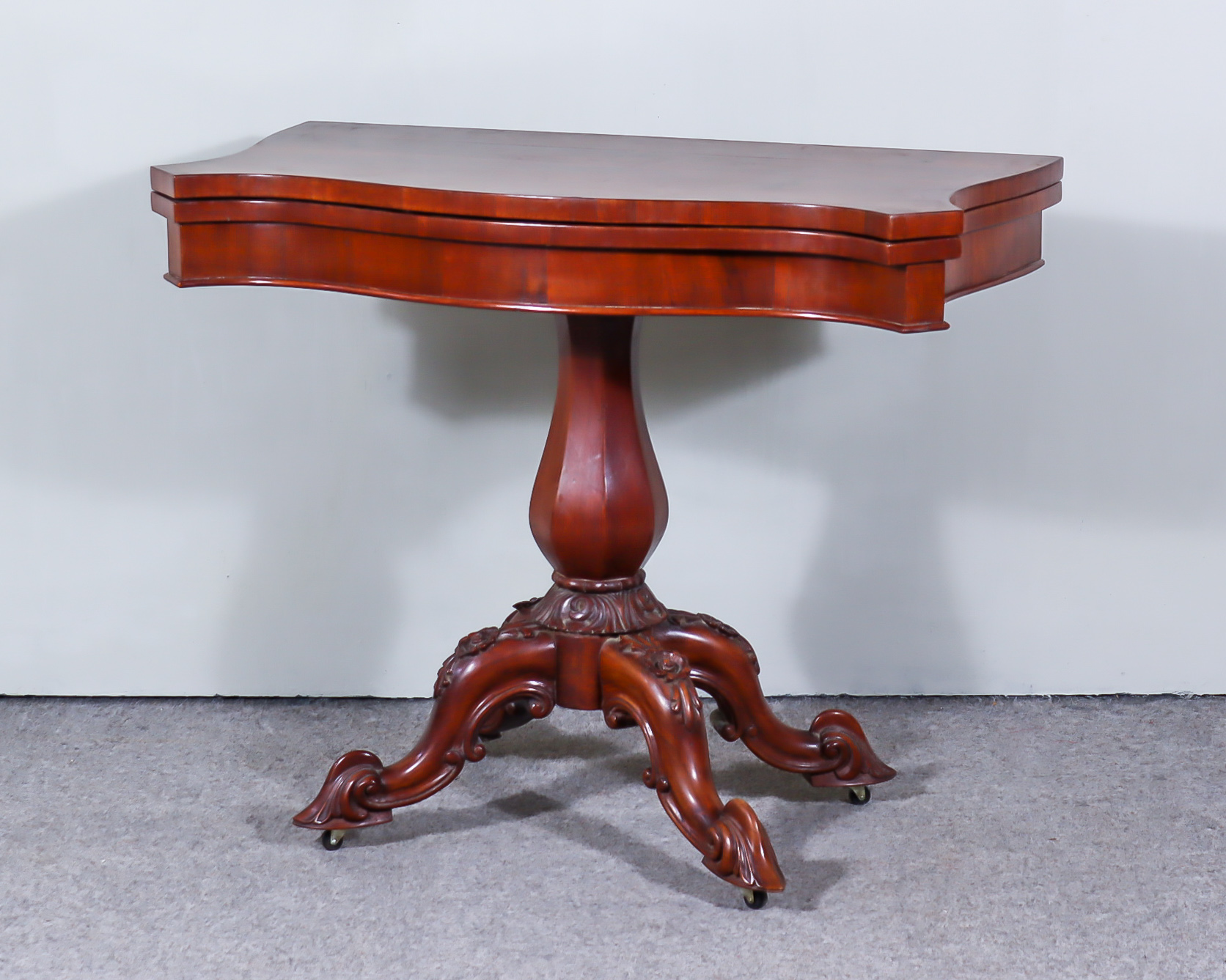 A Mahogany Veneered Card Table, of serpentine outline, baize lined folding top with square edge,