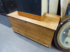 A STRIPPED WOODEN BEDDING BOX, WITH END HANDLES AND HINGED LID, RAISED ON CASTORS