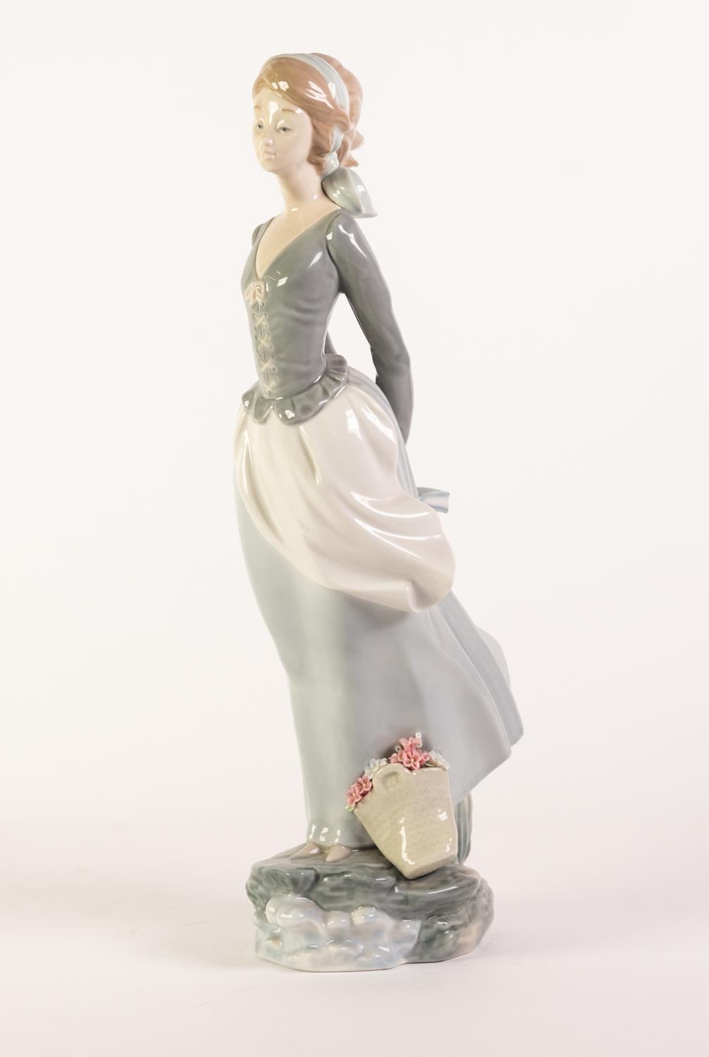 LLADRO PORCELAIN LARGE FIGURE OF A LADY HOLDING A BOOK BEHIND HER BACK, with a basket of flowers