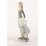 LLADRO PORCELAIN LARGE FIGURE OF A LADY HOLDING A BOOK BEHIND HER BACK, with a basket of flowers