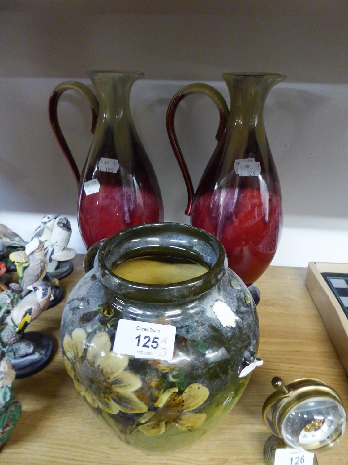 A PAIR OF GREEN AND MAROON GLAZED POTTERY TALL URNS AND A TWO HANDLED VASE (ONE HANDLE MISSING)
