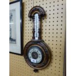 AN EDWARDIAN CARVED WALNUTWOOD ANEROID BAROMETER AND THERMOMETER