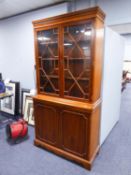 A MODERN YEWWOOD BOOKCASE, HAVING TWO GLAZED DOORS OVER TWO PANEL DOORS (199cm high x 102cm wide x