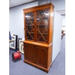 A MODERN YEWWOOD BOOKCASE, HAVING TWO GLAZED DOORS OVER TWO PANEL DOORS (199cm high x 102cm wide x