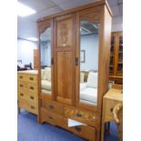 AN EARLY TWENTIETH CENTURY CARVED OAK WARDROBE WITH TWO MIRROR GLAZED DOORS AND THREE DRAWERS