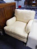 AN EASY ARMCHAIR, COVERED IN CREAM AND GOLD FABRIC