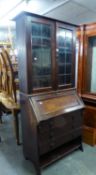 AN EARLY TWENTIETH WALNUT BUREAU BOOKCASE, THE UPPER SECTION ENCLOSED BY TWO LEAD LIGHT DOORS AND