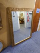 A LARGE GILT FRAMED WALL MIRROR, THE FRAME WALL MIRROR, THE FRAME HAVING EMBOSSED LEAF DECORATION (