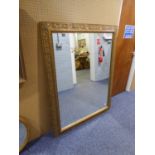 A LARGE GILT FRAMED WALL MIRROR, THE FRAME WALL MIRROR, THE FRAME HAVING EMBOSSED LEAF DECORATION (