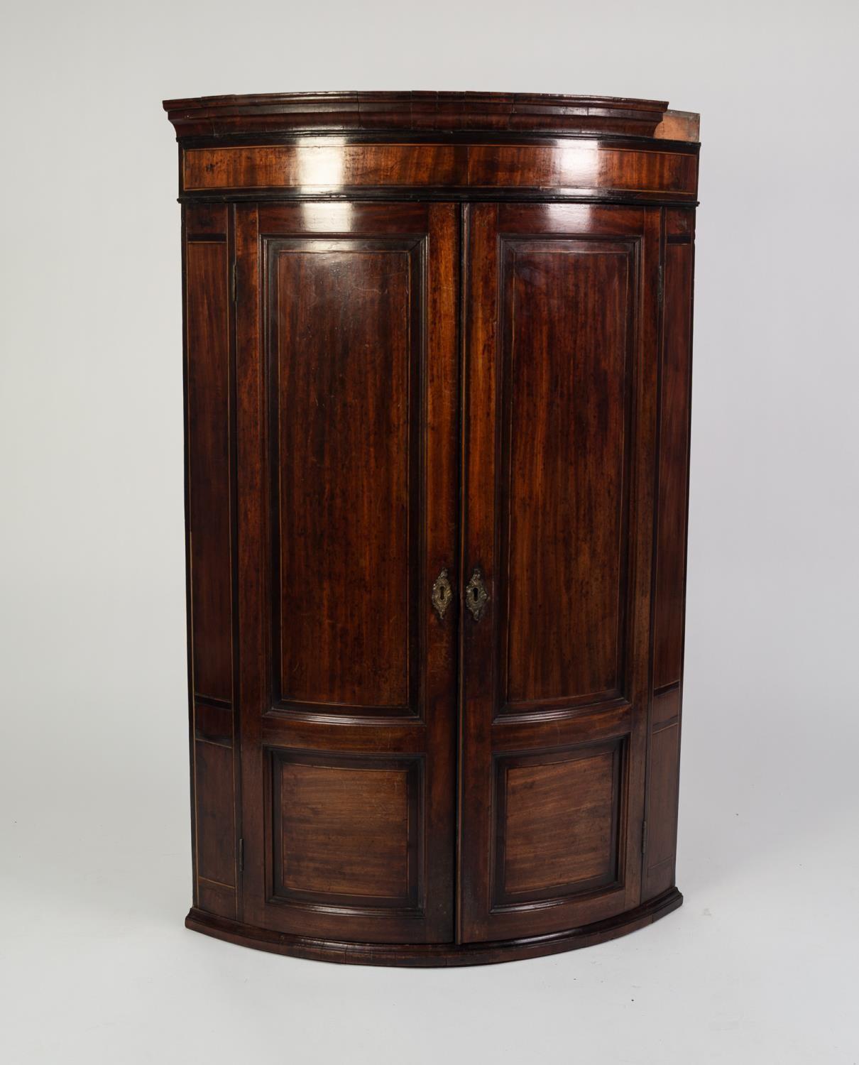 GEORGE III CROSSBANDED AND LINE INLAID MAHOGANY BOW FRONTED CORNER CUPBOARD, the moulded cornice