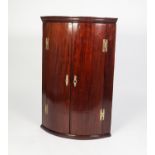 GEORGE III MAHOGANY BOW FRONTED CORNER CUPBOARD, of typical form with moulded cornice, exposed brass