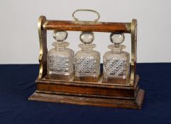 AN EARLY TWENTIETH CENTURY OAK TANTALUS with rubbed EPNS mounts, fitted with three square cut