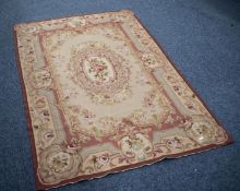 AUBUSSON NEEDLEWORK TAPESTRY RUG with centre oval rose decorated medallion on a fawn field, the