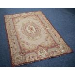 AUBUSSON NEEDLEWORK TAPESTRY RUG with centre oval rose decorated medallion on a fawn field, the