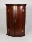 GEORGE III MAHOGANY CROSSBANDED OAK BOW FRONTED CORNER CUPBOARD, of typical form with exposed