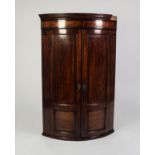 GEORGE III CROSSBANDED AND LINE INLAID MAHOGANY BOW FRONTED CORNER CUPBOARD, the moulded cornice