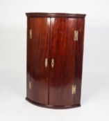 GEORGE III MAHOGANY BOW FRONTED CORNER CUPBOARD, of typical form with moulded cornice, exposed brass