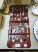 COLLECTION OF EIGHTEEN ELECTROPLATED AND CHROME PLATED SOUVENIR SPOONS ON WOODEN MURAL DISPLAY RACK,