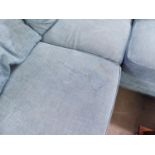 A LARGE 'L' SHAPED SETTEE COVERED IN BLUE FABRIC ON BUN FEET