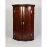 GEORGE III MAHOGANY CROSSBANDED OAK BOW FRONTED CORNER CUPBOARD, of typical form with exposed