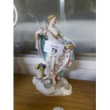 AN EARLY TWENTIETH CENTURY CONTINENTAL CERAMIC FIGURE OF A SEMI-DRAPED FEMALE FIGURE HOLDING A