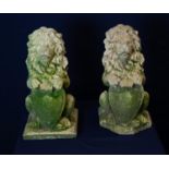 A PAIR OF RECONSTITUTED LIONS HOLDING SHIELDS,  ONE BASE DAMAGED (A.F.) (40cm HIGH )