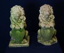 A PAIR OF RECONSTITUTED LIONS HOLDING SHIELDS,  ONE BASE DAMAGED (A.F.) (40cm HIGH )