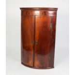 GEORGE III FIGURED MAHOGANY BOW FRONTED CORNER CUPBOARD, of typical form with dentil moulded