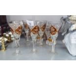A SET OF SIX CUT GLASS STEM WINES, THE CONICAL BOWLS WITH AMBER STAINED AND FLORAL ENGRAVED PANELS