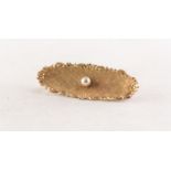 A GOLD CONCAVE OVAL BROOCH, textured with floral and scroll border and set with centre pearl, 1 3/4"